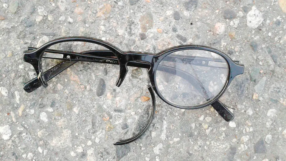 Trasiga glasögon på asfalt.