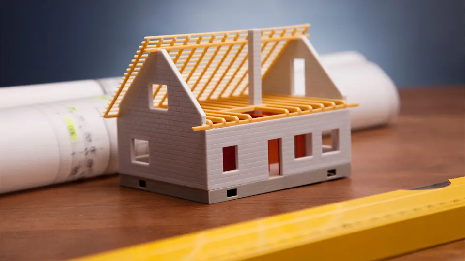 Modell av ett vitt hus, en ritning och ett gult vattenpass
