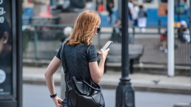 Kvinna håller i en mobiltelefon och läser på skärmen.